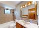 Bathroom features a tub with tiled walls and a wood vanity with a cream-colored sink at 4071 Dekle Ave, North Port, FL 34286