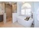 Bright bathroom featuring a soaking tub with a tray, shuttered window, and a glass enclosed shower at 4216 Bur St, Port Charlotte, FL 33948