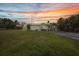 Charming single-story home featuring a large grassy lawn with tropical trees at a colorful sunset at 426 Burland St, Punta Gorda, FL 33950