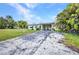 Exterior view of home featuring a long driveway with carport and tropical landscaping at 426 Burland St, Punta Gorda, FL 33950