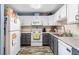 Well-lit kitchen with white cabinets, stainless steel sink, grey lower cabinets, and wood-look flooring at 4702 Westwood Dr, Punta Gorda, FL 33982