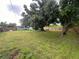Spacious backyard featuring lush green grass, mature trees, and a wood fence providing privacy at 481 Reading Nw St, Port Charlotte, FL 33952