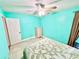 A turquoise bedroom with tile flooring, ceiling fan, and a matching comforter on the bed at 481 Reading Nw St, Port Charlotte, FL 33952