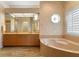 Luxurious bathroom featuring wood-look tile floors, double sinks, and a large soaking tub with stylish fixtures at 5023 Key Largo Dr, Punta Gorda, FL 33950