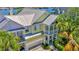 Inviting yellow two-story home with metal roof, dual balconies, lush tropical landscaping, and pergola-covered driveway at 936 Hemingway Cir, Tampa, FL 33602