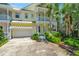 Bright yellow two-story home featuring double balconies, white trim, tropical landscaping, and a convenient two-car garage at 936 Hemingway Cir, Tampa, FL 33602