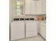 Well-lit laundry room featuring white washer and dryer units, ample cabinetry, and a practical sink area at 936 Hemingway Cir, Tampa, FL 33602