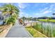 Waterfront backyard with a wooden dock, seating, and tropical landscaping at 9582 Arsipe Cir, Port Charlotte, FL 33981