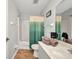 Well-lit bathroom features a shower with a green ombre curtain and brown tile floors at 9582 Arsipe Cir, Port Charlotte, FL 33981