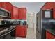 Charming kitchen with stainless steel appliances, granite countertops, and red cabinets leading to the laundry room at 9582 Arsipe Cir, Port Charlotte, FL 33981