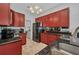 Modern kitchen with black appliances, granite countertops, and ample red cabinet storage with a laundry room nearby at 9582 Arsipe Cir, Port Charlotte, FL 33981