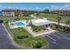 Aerial view of a community pool with a building, palm trees, nearby condos, parking spaces, and well-maintained green spaces at 101 N Marion Ct # 133, Punta Gorda, FL 33950