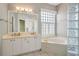 Main bathroom featuring double sinks, a soaking tub, and a glass block window at 10263 Shadow Run Cir, Punta Gorda, FL 33955