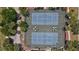 Aerial view featuring pristine blue tennis courts with meticulous landscaping and mature trees at 10263 Shadow Run Cir, Punta Gorda, FL 33955