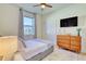 Cozy bedroom featuring a modern dresser, ceiling fan and bright window overlooking outdoor space at 122 Arrow Ln, Rotonda West, FL 33947