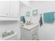 This powder room features a bright vanity, a framed seashell wall decor, and a coordinated teal hand towel at 14257 Heritage Landing Blvd # 1115, Punta Gorda, FL 33955
