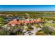 An aerial view of the clubhouse showing the community pool, tennis courts, and a surrounding lush landscape at 1470 Hyssop Loop, North Port, FL 34289