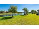 Picturesque backyard view overlooking a serene lake, lush green lawn, and mature trees on a sunny day at 1470 Hyssop Loop, North Port, FL 34289