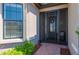 View of the front door with a screen, decorated with a wreath, and a chair to the side at 1470 Hyssop Loop, North Port, FL 34289