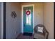 A close-up of a teal front door with decorative wreath, chair with bird pillow and decorative wall art at 1470 Hyssop Loop, North Port, FL 34289
