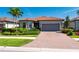 Beautiful single-story home with a red tile roof, a brick driveway, well-maintained landscaping, and a two-car garage at 1470 Hyssop Loop, North Port, FL 34289