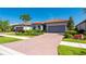 Charming single-story home with a red tile roof, brick driveway, lush landscaping, and a two-car garage at 1470 Hyssop Loop, North Port, FL 34289