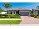 Inviting single-story home with a red tile roof, brick driveway, manicured landscaping, and a two-car garage at 1470 Hyssop Loop, North Port, FL 34289