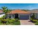 Charming single-story home featuring a red tile roof, a two-car garage, and tropical landscaping in the front yard at 1470 Hyssop Loop, North Port, FL 34289