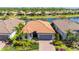 Inviting single-story home boasts a red tile roof, two-car garage, and lush landscaping, overlooking a serene lake at 1470 Hyssop Loop, North Port, FL 34289
