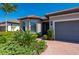 Close-up of a home's front exterior showcasing a brick walkway, lush landscaping, and a screen door entrance at 1470 Hyssop Loop, North Port, FL 34289