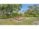 Landscaped backyard with lush green grass, mature trees, fire pit area, and tropical foliage at 1761 Okolona St, North Port, FL 34287