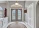 Elegant foyer showcasing double doors, neutral walls, tiled flooring, and stylish light fixture at 1761 Okolona St, North Port, FL 34287