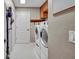A modern laundry room with a white washer and dryer set, cabinet storage and easy access to other rooms at 1761 Okolona St, North Port, FL 34287