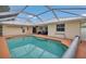 Backyard swimming pool enclosed in a screened-in patio, surrounded by a spacious deck and lush landscaping at 1761 Okolona St, North Port, FL 34287