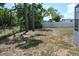 A spacious backyard with trees, grass, and a partial view of a neighboring fence at 21275 Austin Ave, Port Charlotte, FL 33952