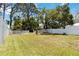 Fenced-in backyard with a green lawn and surrounding trees, perfect for outdoor activities at 233 N New York Ave, Englewood, FL 34223