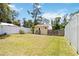 Spacious fenced-in backyard with a yellow house and grassy area, ideal for outdoor enjoyment at 233 N New York Ave, Englewood, FL 34223