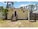 View of the back of the home with yellow siding, door, and a small backyard space at 233 N New York Ave, Englewood, FL 34223