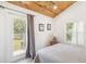 Bedroom with wood-paneled ceiling, white walls, a deck door, and a backyard view at 233 N New York Ave, Englewood, FL 34223