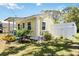 Side view of charming yellow cottage with a well-maintained, grassy yard and a white privacy fence at 233 N New York Ave, Englewood, FL 34223