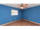 Bedroom with blue walls, wood-look laminate flooring and a ceiling fan with lights at 238 Mark Twain Ln, Rotonda West, FL 33947