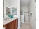 Bathroom with a shower, tiled floor, and dark wood vanity with double sinks and plenty of lighting at 24312 Westgate Blvd, Port Charlotte, FL 33980