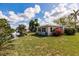 Charming single-story home featuring a waterfront view, lush lawn, and vibrant bougainvillea bushes at 3129 Buttonwood Pl, Punta Gorda, FL 33950