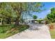 Charming single-story home featuring a lush front yard with mature trees, complemented by a long driveway on a sunny day at 3129 Buttonwood Pl, Punta Gorda, FL 33950