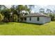 A charming single-story home features a well-manicured lawn and a serene, wooded backdrop at 355 Milton St, Port Charlotte, FL 33954
