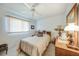 Bright bedroom features a ceiling fan, large window, dresser with vintage lamps, and a comfy looking bed at 4055 Alwick Ln, North Port, FL 34287