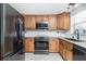 A modern kitchen featuring wooden cabinets, black appliances, granite countertops and tile flooring at 416 Allen St, Punta Gorda, FL 33950