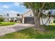 Beautiful home with a brick driveway, a gray two-car garage, and lush green lawn under a tree at 425 Corrientes Cir, Punta Gorda, FL 33983