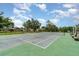 An outdoor tennis court with green and gray surface surrounded by mature trees at 541 Wekiva River Ct # 94, Englewood, FL 34223
