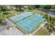 Aerial view of tennis and pickleball courts with shade pavilions, seating, parking, and a scenic pond at 541 Wekiva River Ct # 94, Englewood, FL 34223